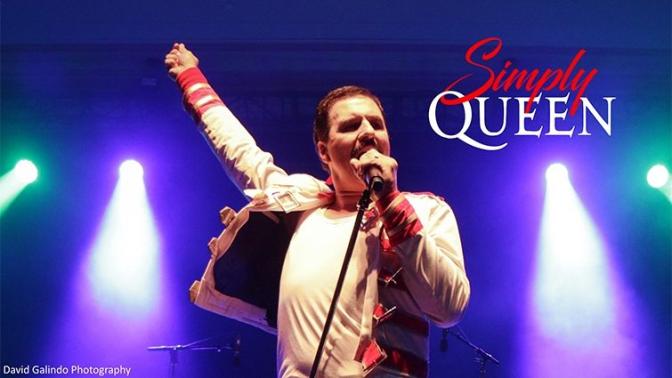 tribute artist with one arm raised and holding a microphone who closely resembling freddie mercury