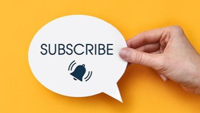 Hand holding a speech bubble with the word "SUBSCRIBE" and a notification bell icon on a bright yellow background.