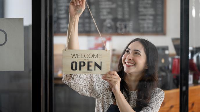 shop keeper hanging a welcome sign in a shop window