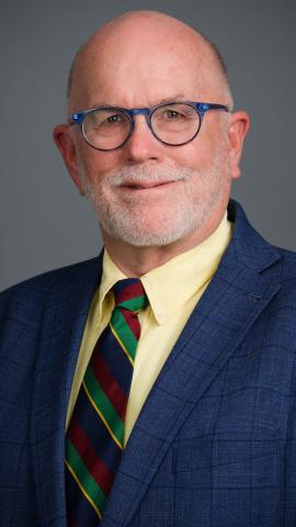 man in glasses wearing a blue suit jacket and yellow shirt