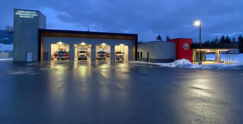 A wide shot of a fire hall taken at night, with four bay windows open and showing the fire engines ready to depart if called out.