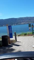 Fourth St. Park sign with public beach access next to a lake with mountainous terrain in the background.