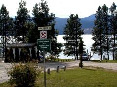 Coral Beach Park sign with a view of the lake, trees, and a boat dock in the background.