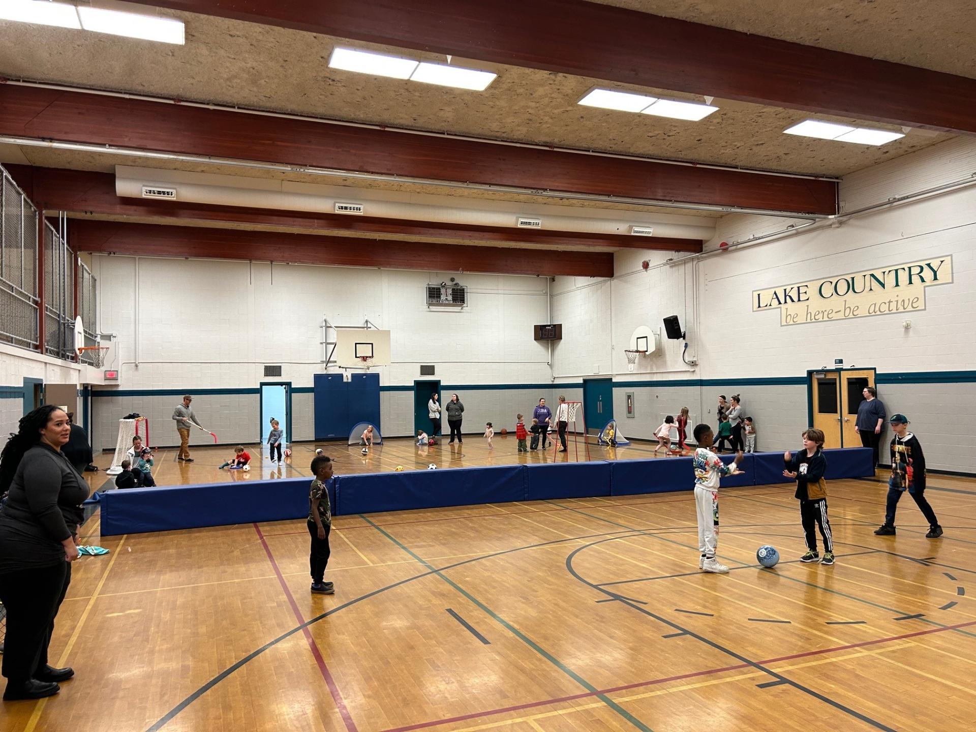 young children playing basketball and soccer in a gym